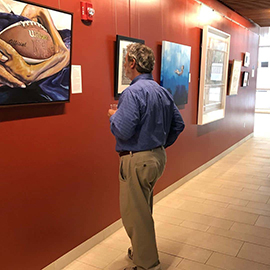 Art enthusiast looks on one of the paintings in the exhibition.